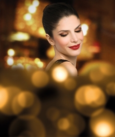 Mujer maquillada sonriendo, luces de fondo
