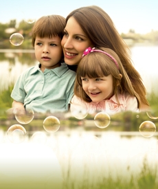 Mujer sonriendo y abrazando a dos niños. Todos muy alegres