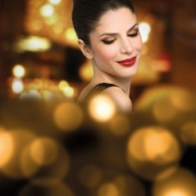 Mujer maquillada sonriendo, luces de fondo