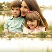 Mujer sonriendo y abrazando a dos niños. Todos muy alegres